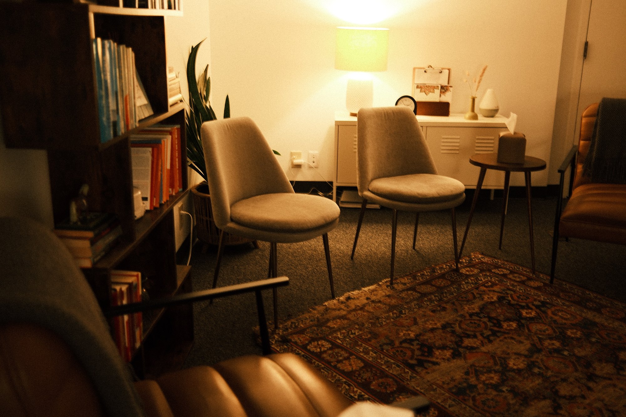 A leather chair beside soft lamps and warm artwork in the Anomaly Therapy office.