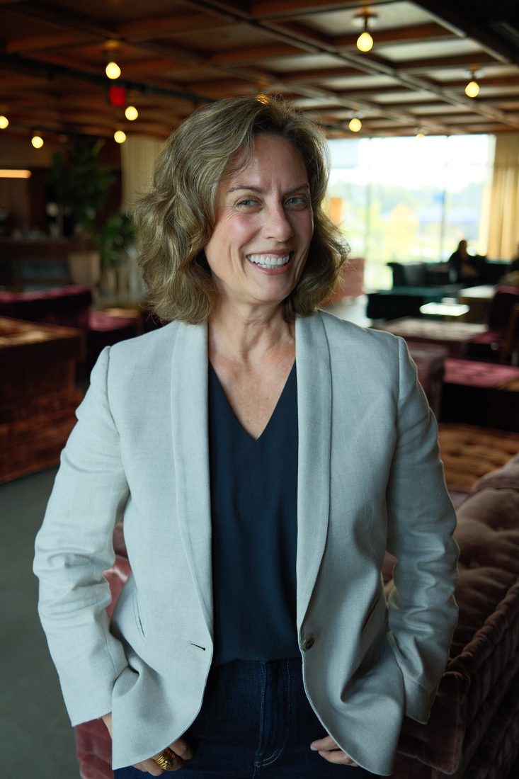 Ann Hatcher smiling in a lounge, wearing a light blazer.
