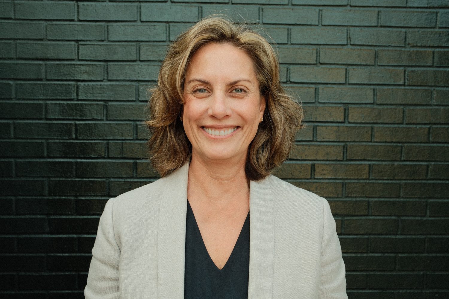 Ann Hatcher, MS, MBA, smiling headshot in front of a brick wall.