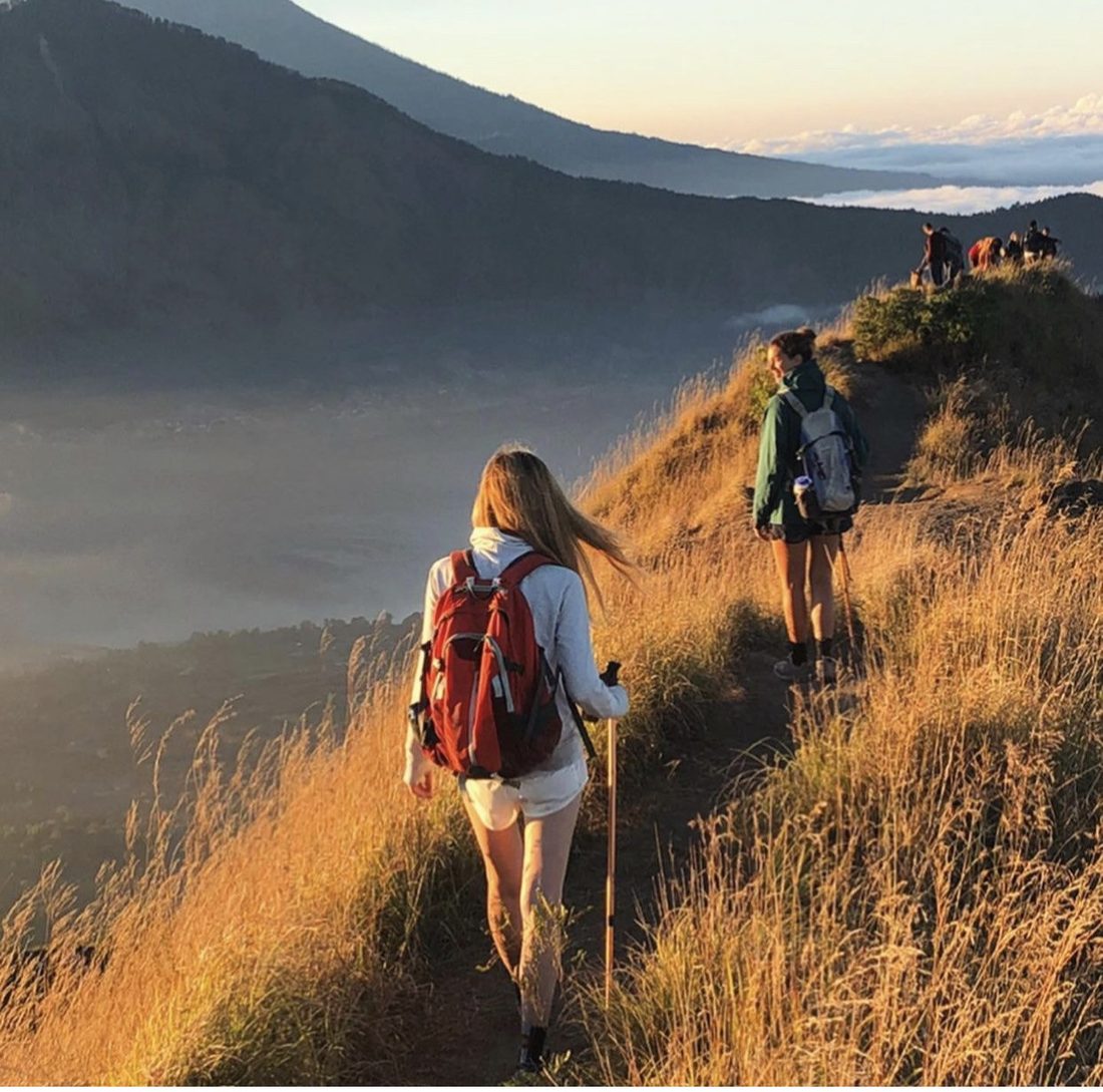Cayce Smith and a friend hiking along a ridge at sunset.
