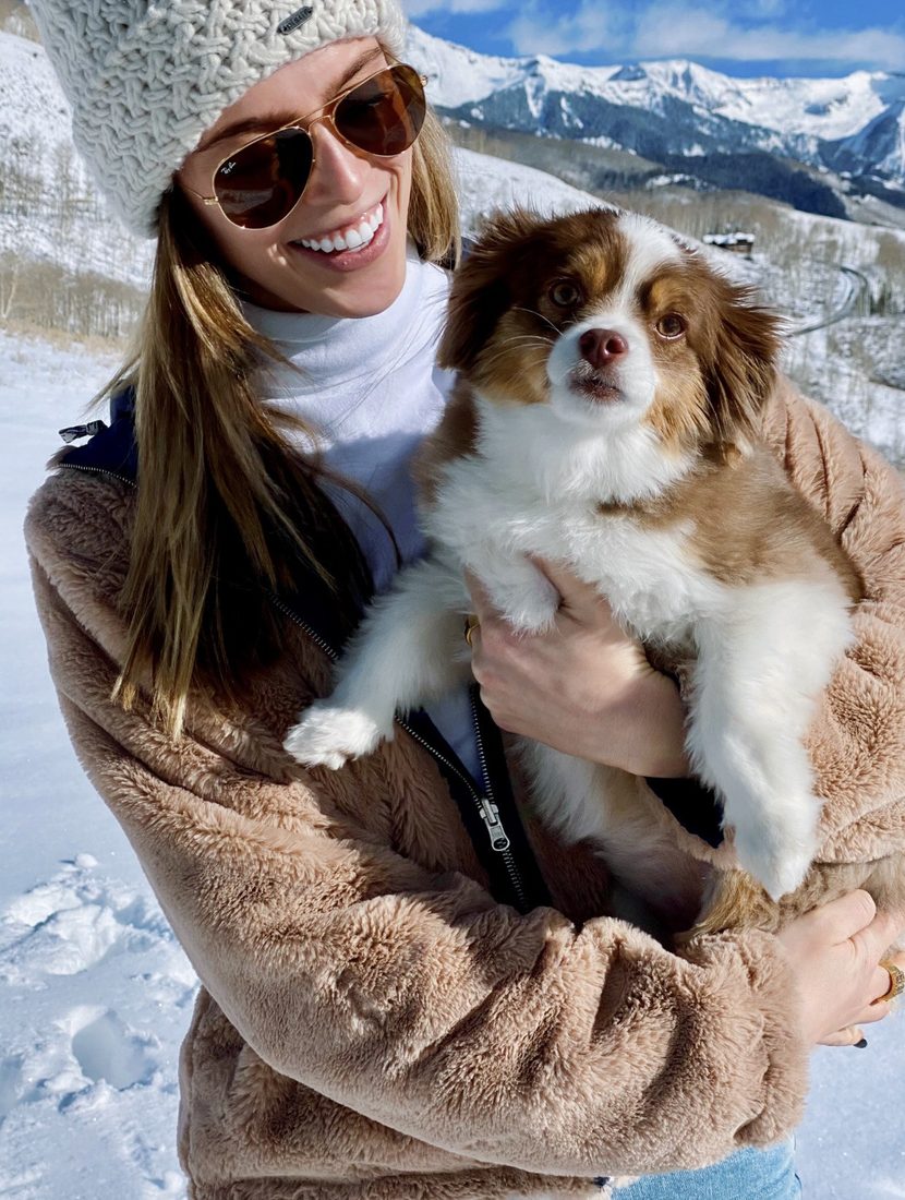 Cayce Smith smiling in the snow while holding her dog, Margot.
