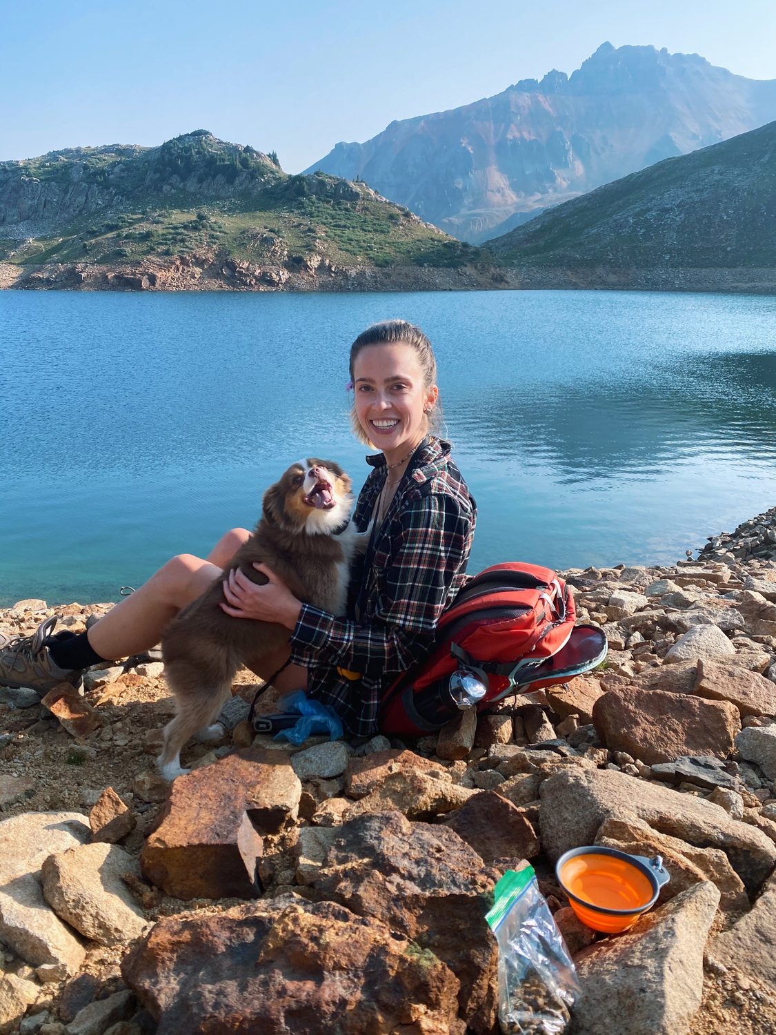 Cayce Smith sitting by a mountain lake holding her dog, Margot.