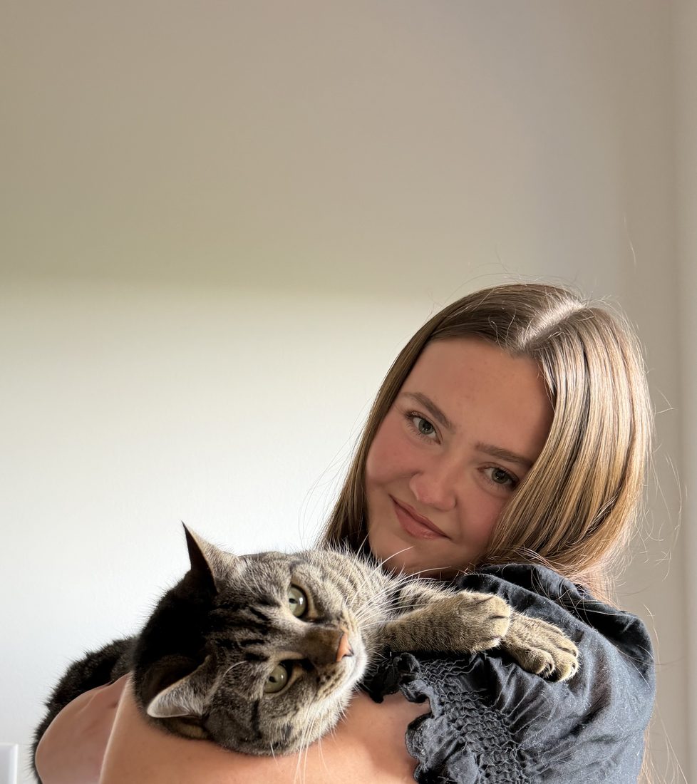 Elena Godbout smiling while holding her tabby cat.