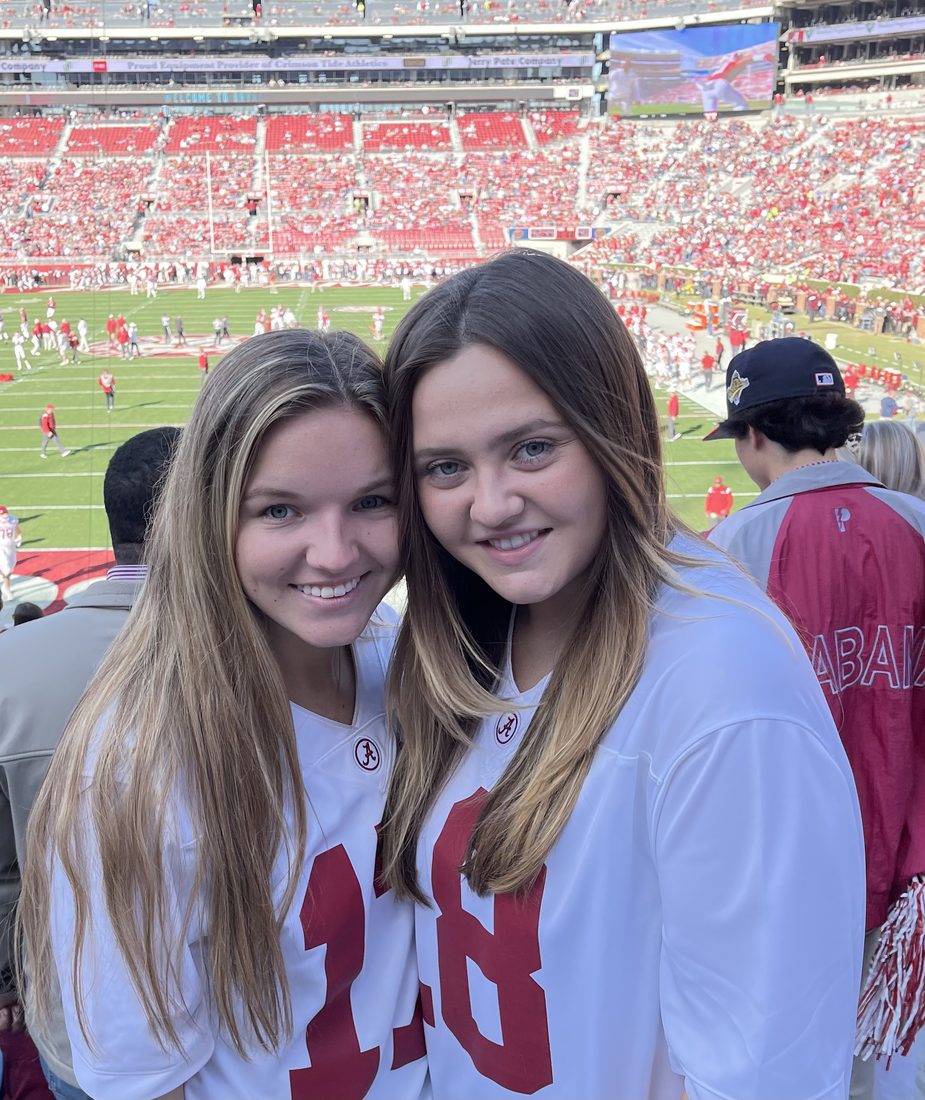 Elena Godbout with a friend at a college football game, wearing Alabama jerseys.