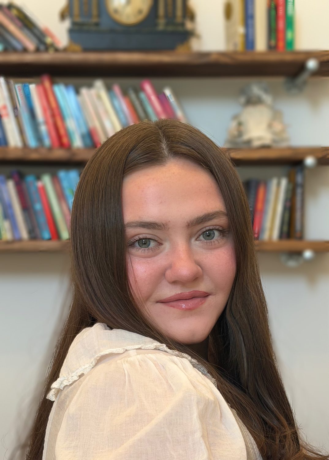 Elena Godbout smiling in front of a bookshelf.