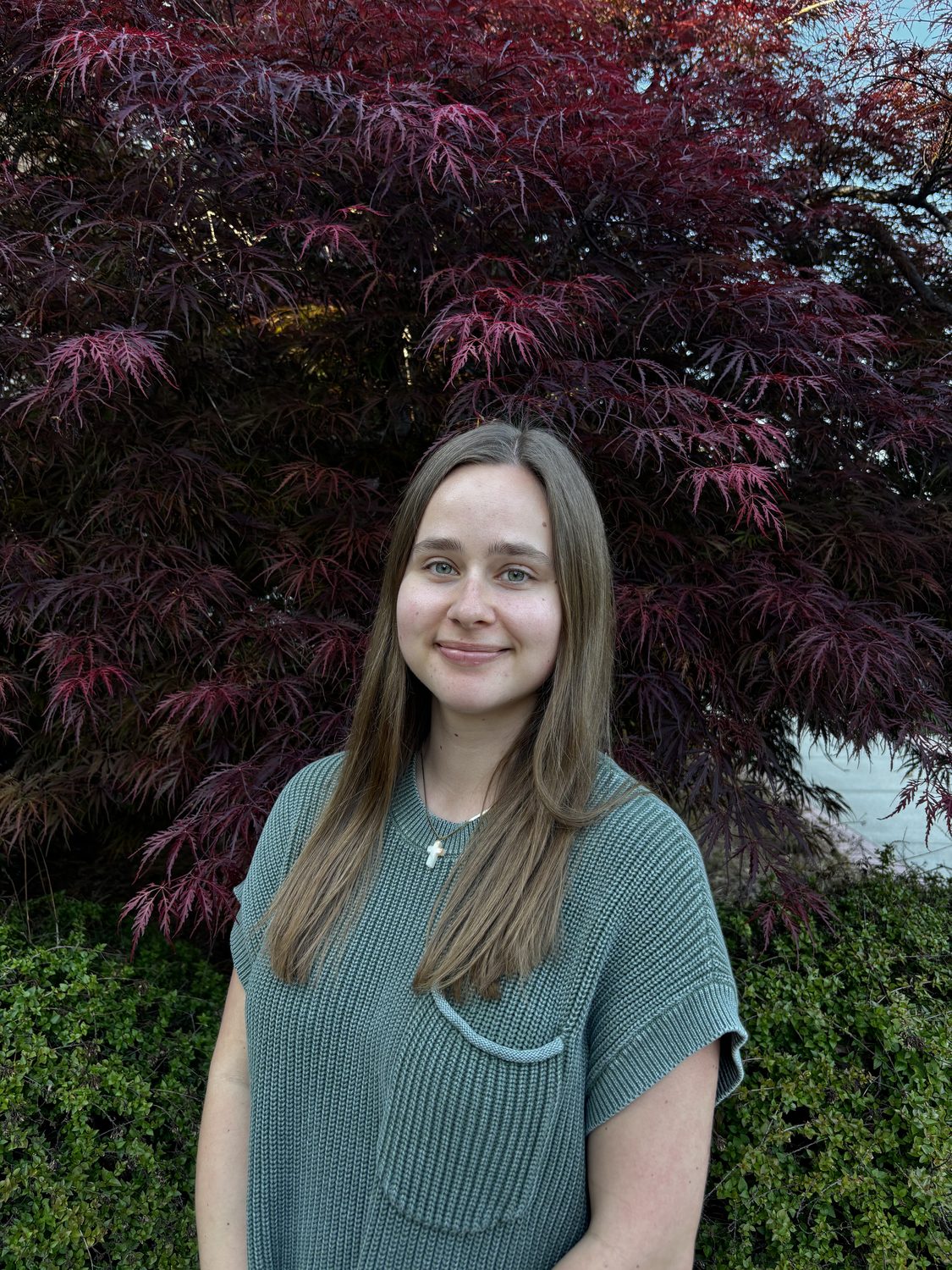 Jillee Walter, Clinical Intern, standing in front of a Japanese maple tree.