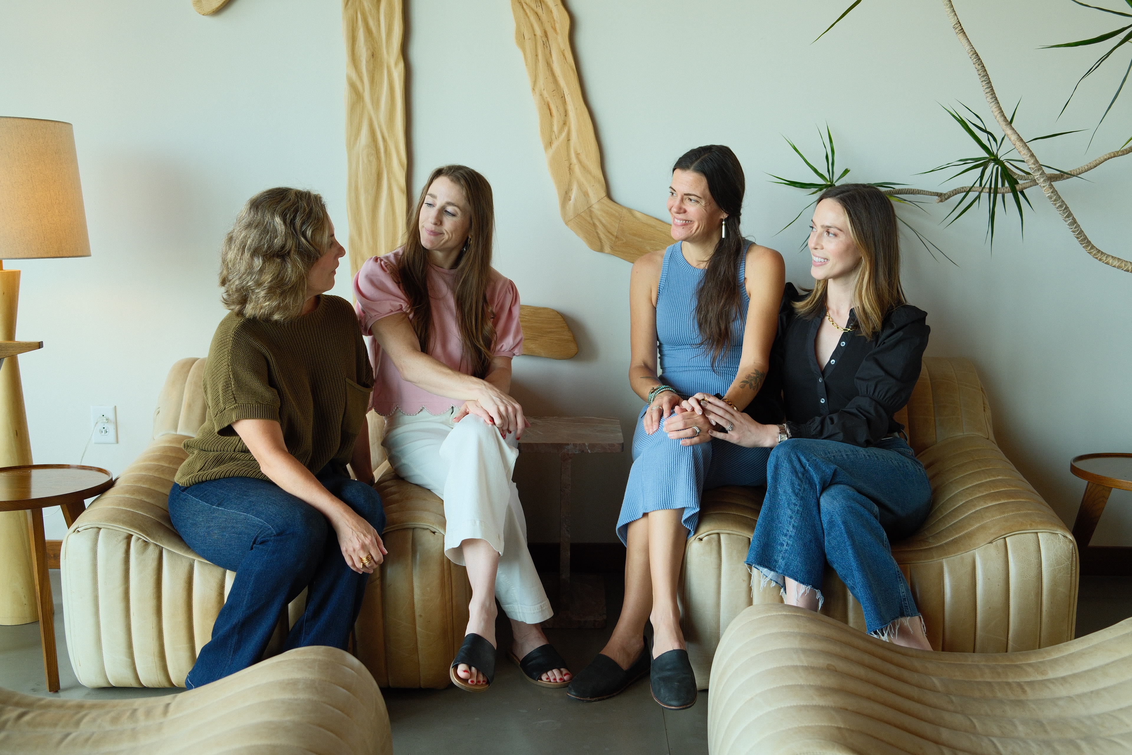 The Anomaly Therapy team in conversation on a tan leather couch in the office lounge.